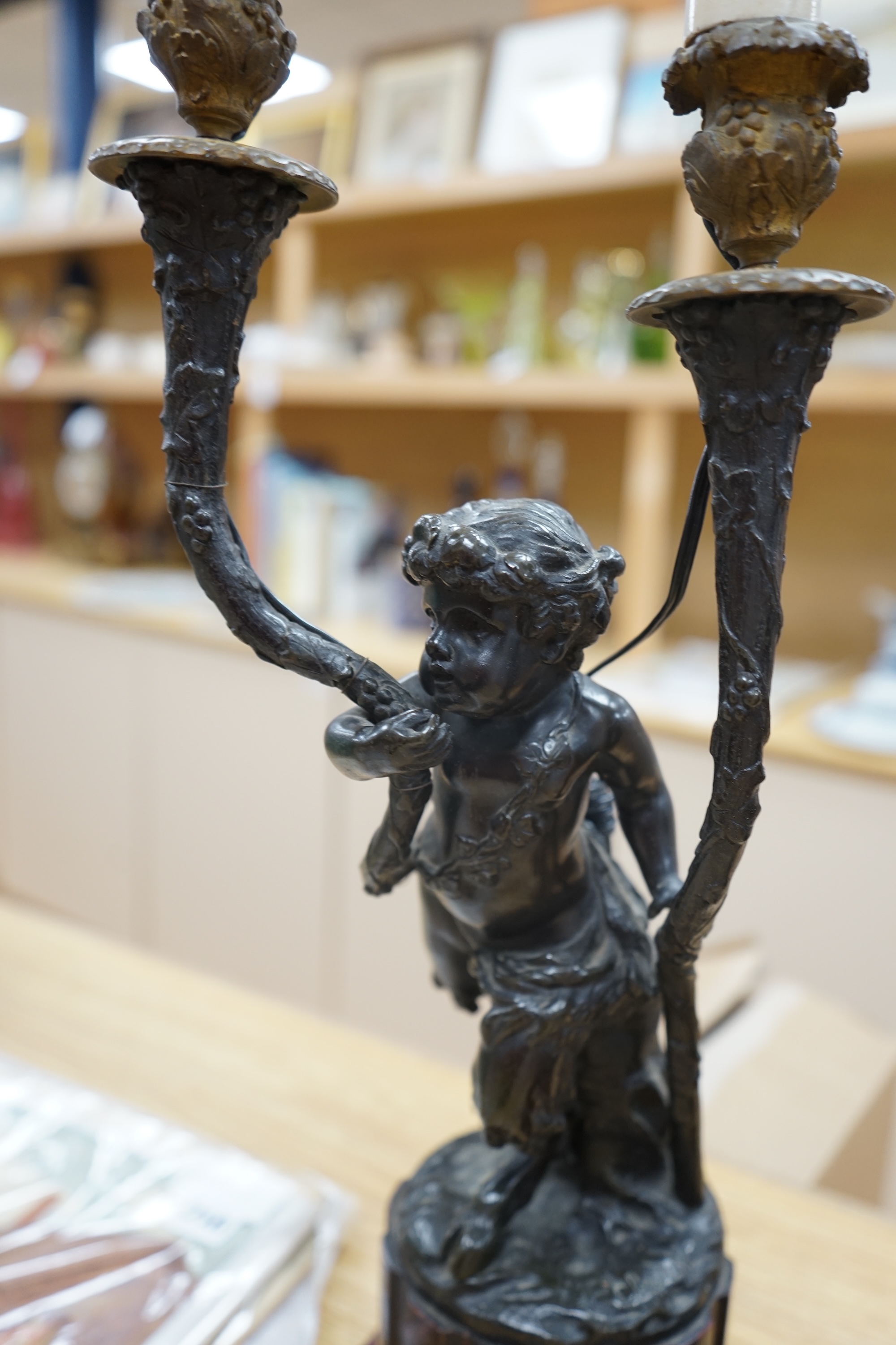 A pair of French bronze cupid twin candelabra with leaf shaped twin arms upon rouge marble fluted columns, after Clodion c.1840, 44cm high, excluding the fitting. Condition - fair